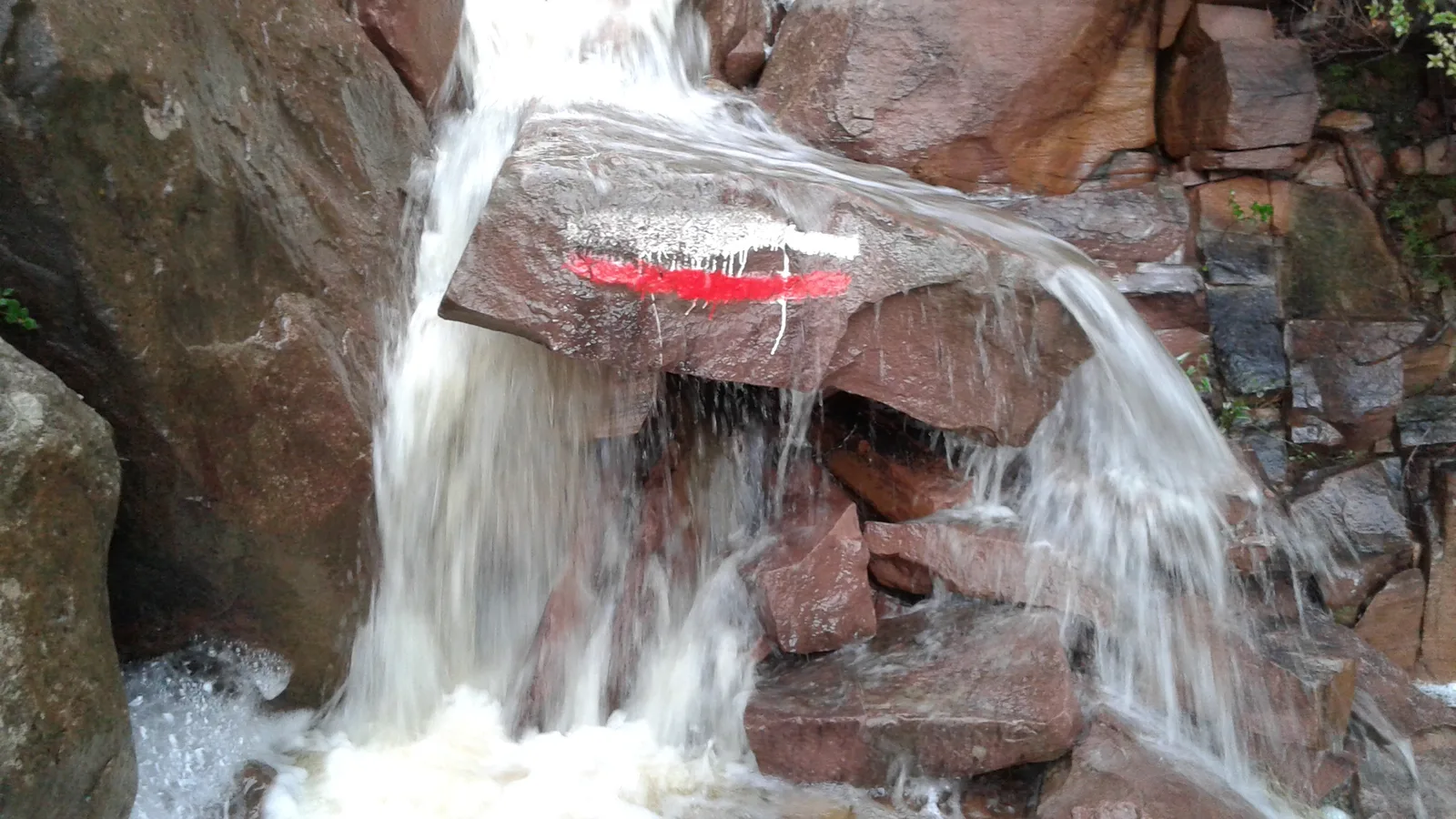 Waterfall and GR 10 red and white blaze at Canal del Garbí.